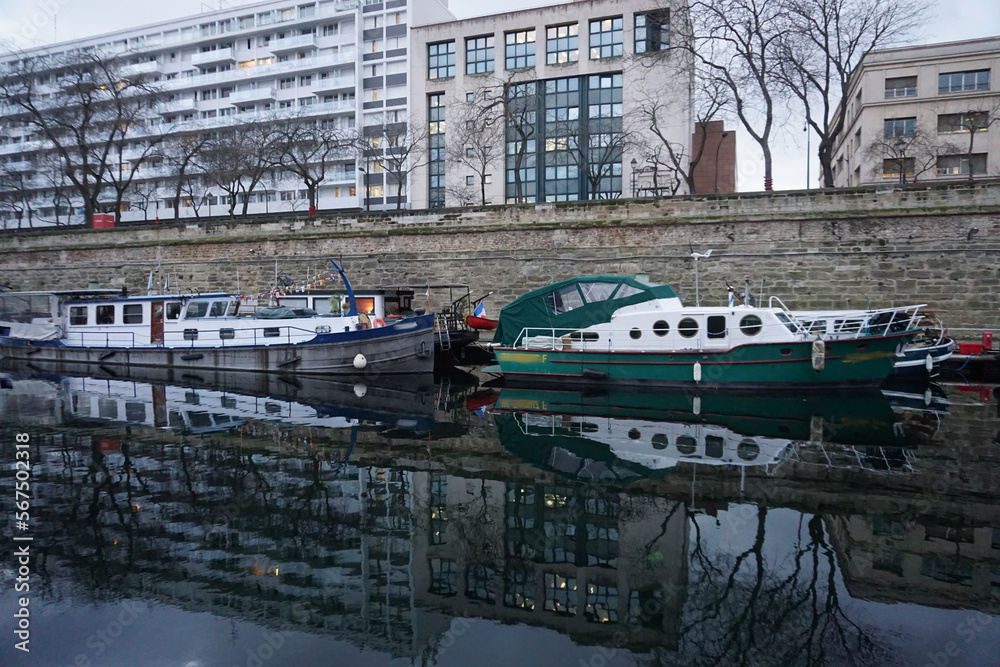 Obraz premium mirror reflection of the moored boats and buildings in the river Seine in downtown Paris, France