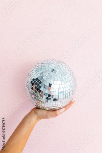 Hand holding disco ball on light pink background