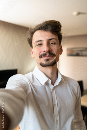 Portrait of young adult caucasian man in apartment wear white shirt