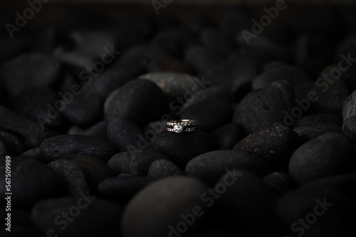 Set of wedding rings balanced on dark river rock, close up, copy space. 