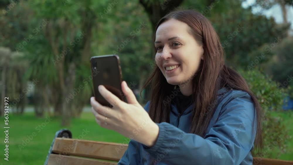 Happy young woman making selfie or video call in green public park. Connection technology of new generation. Happy young woman making selfie or video call in green public park. Connection technology of new generation.