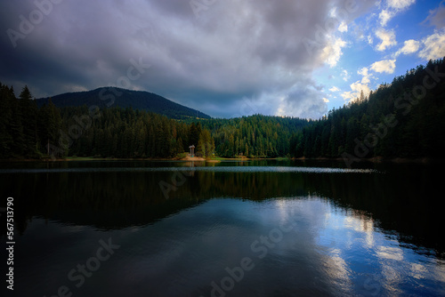 Mountain lake among mountains with reflection, sky, clouds