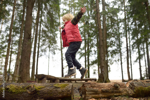 Little boy in red vest is playing branch and having fun in forest on early spring day. Activity for children. Outdoor recreation for family