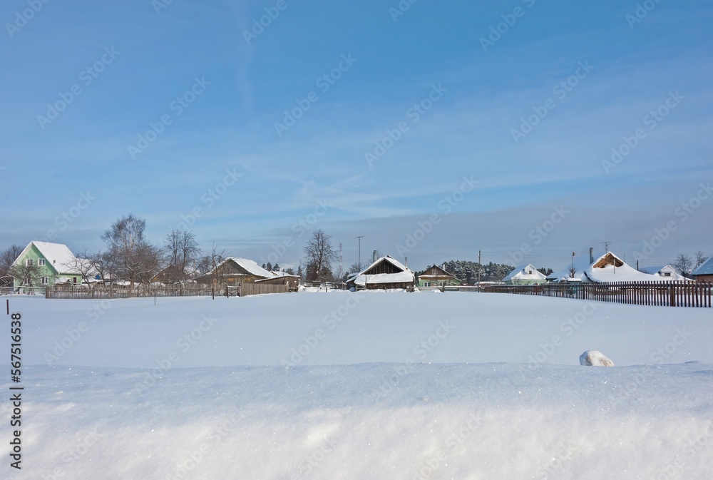 There is a lot of snow in front of the houses of the village