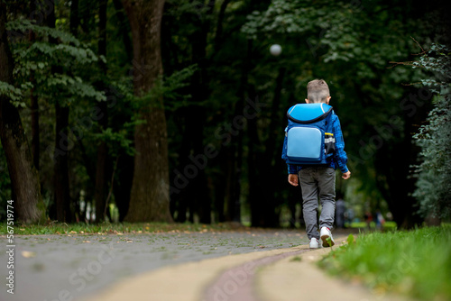 Fototapeta Naklejka Na Ścianę i Meble -  Little boy with backpack going to school. Rear view. First grader