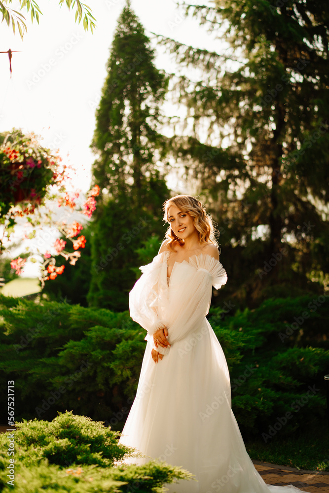 beautiful bride in a white delicate dress in the park at sunset.