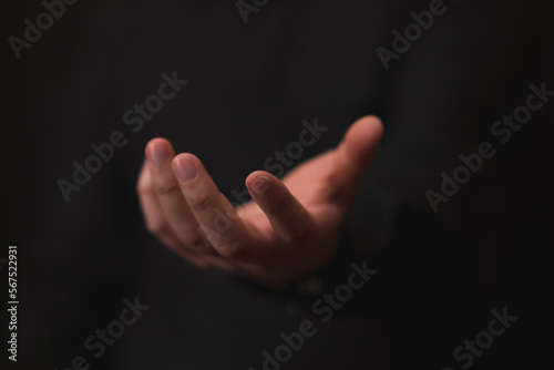 hand outstretched in gesture of giving or receiving, black background
