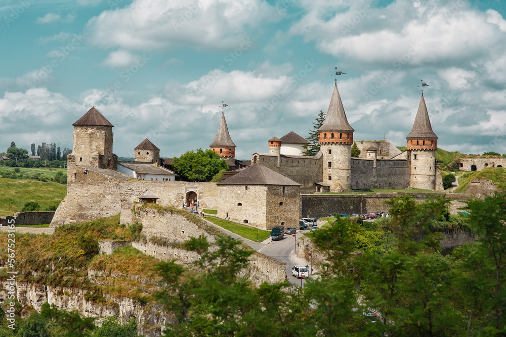 Famous historical fortified old medieval castle of Kamianets-Podilskyi in Ukraine, ancient fortress and tourist attraction with towers, thick walls, bridge in summer day, blue sky with textured clouds