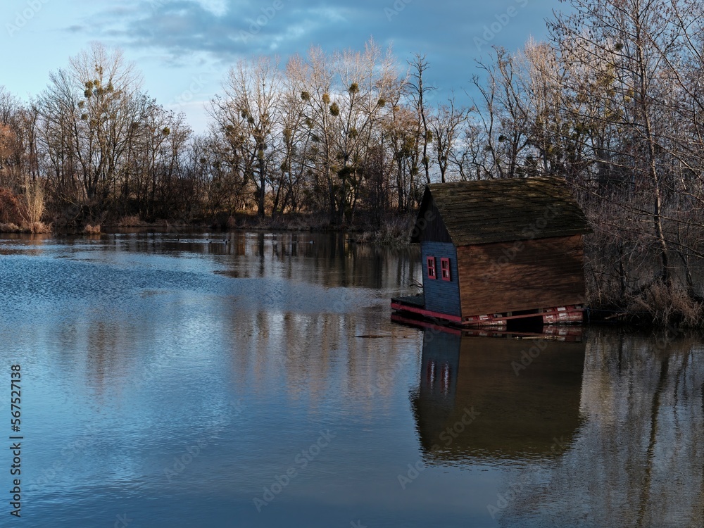 Wooden houseboat with red windows on the Little Dunaj river in the village of Zalesie, Slovakia