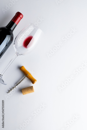 Bottle of red wine, glass and corkscrew on white background, with copy space