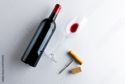 Bottle of red wine, glass and corkscrew on white background, with copy space