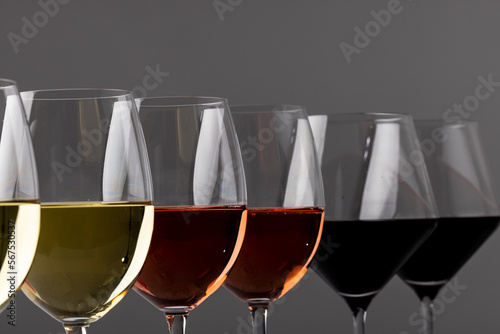 Glasses with red, rose and white wine on grey background, with copy space