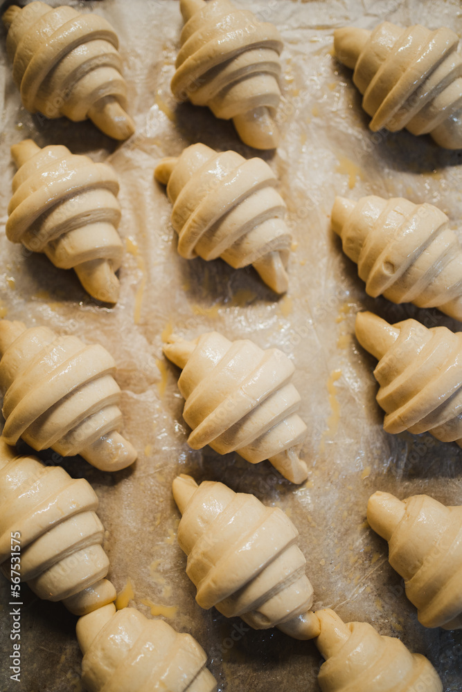 High view of several fresh uncooked croissants in row inside a bakery High view of several fresh uncooked croissants in row inside a bakery