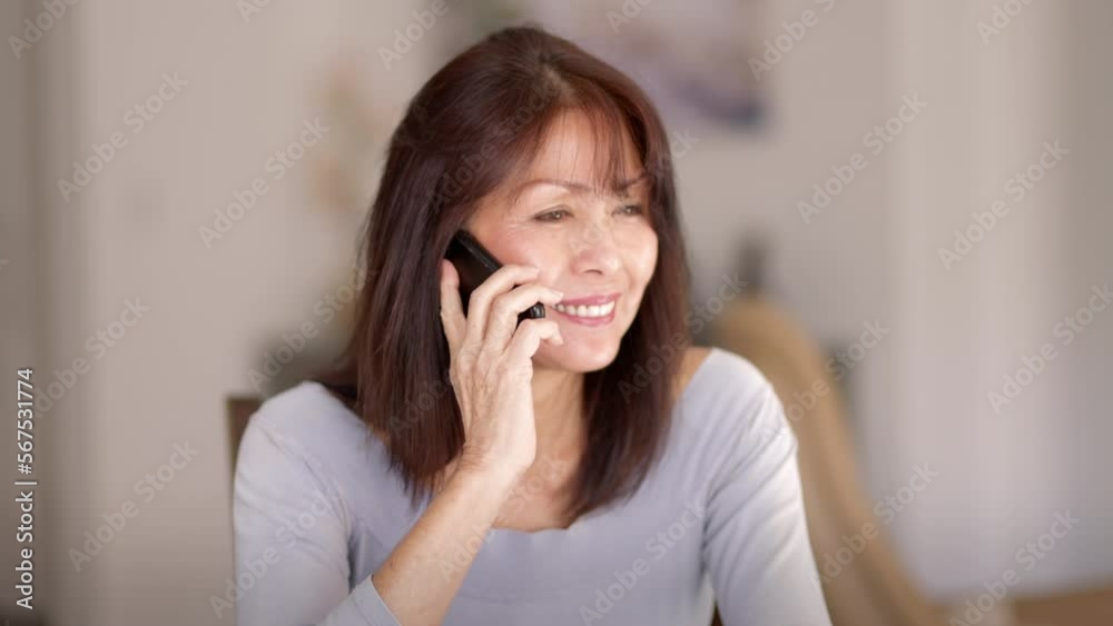 Smiling attractive mature woman relaxing talking on mobile phone sitting in leisure home living room Smiling attractive mature woman relaxing talking on mobile phone sitting in leisure home living room