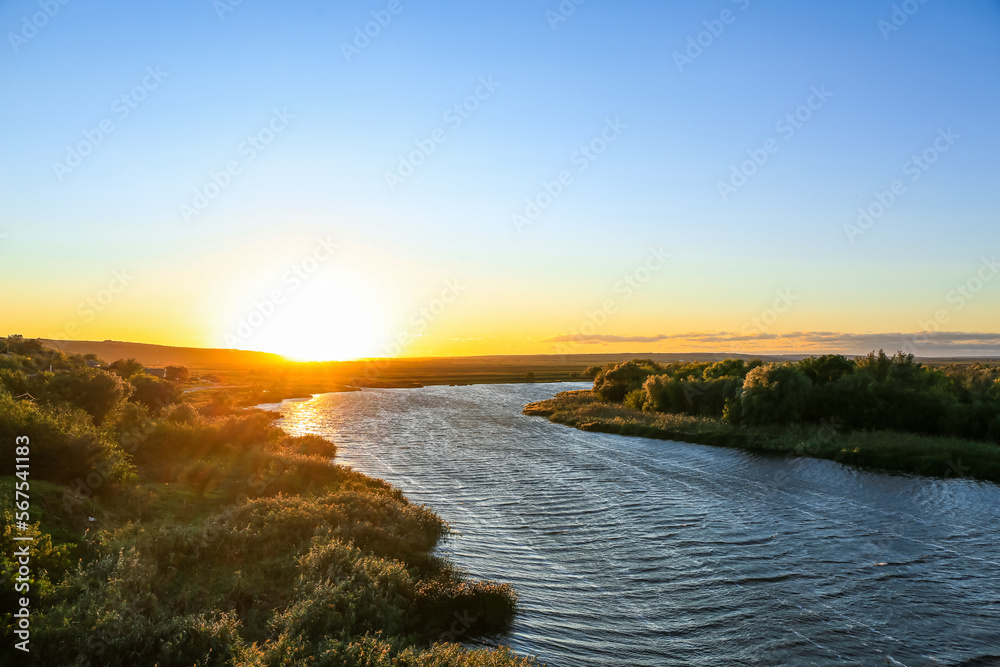 View of beautiful river with green bushes at sunset