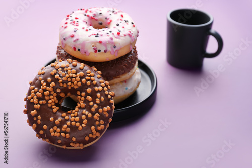 Plate with sweet donuts on lilac background