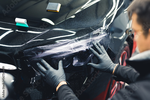 Lamp darkening process - car detailing procedure performed by a professional worker. Back view. Blurred mechanic in the foreground. High quality photo