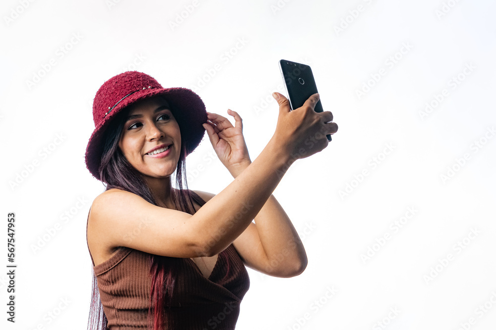 Latin girl taking a picture with her mobile phone. woman in a video call with her mobile device. Portrait of a Colombian girl on a white background. using app Latin girl taking a picture with her mobile phone. woman in a video call with her mobile device. Portrait of a Colombian girl on a white background. using app
