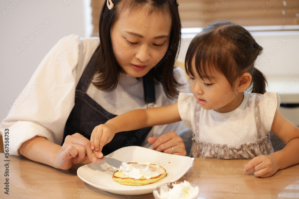 ホットケーキにクリームを塗る親子