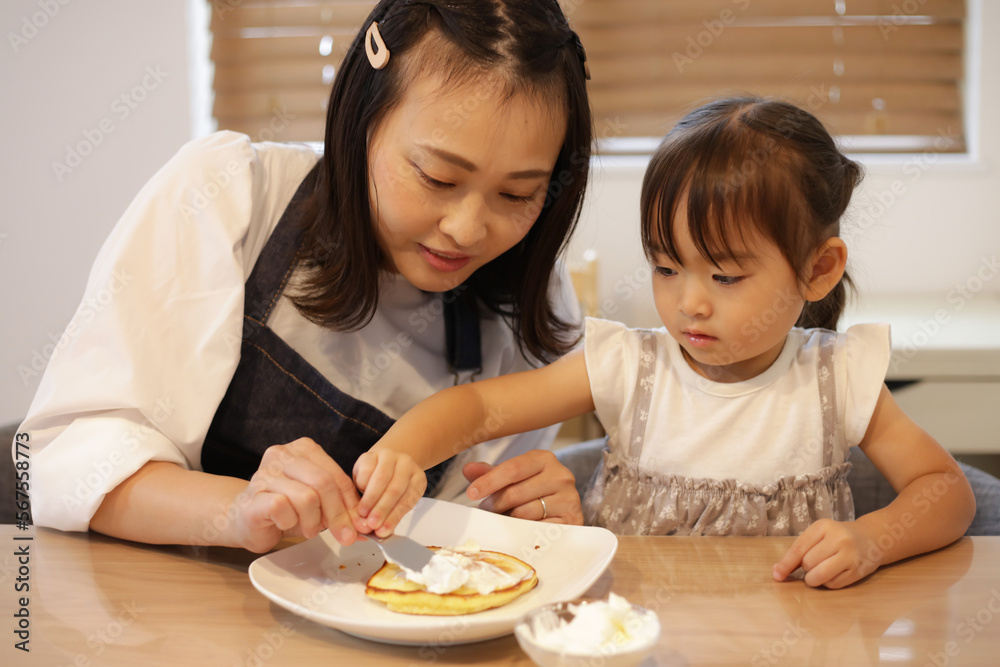 ホットケーキにクリームを塗る親子