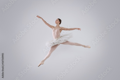 Young ballerina practicing dance moves on white background
