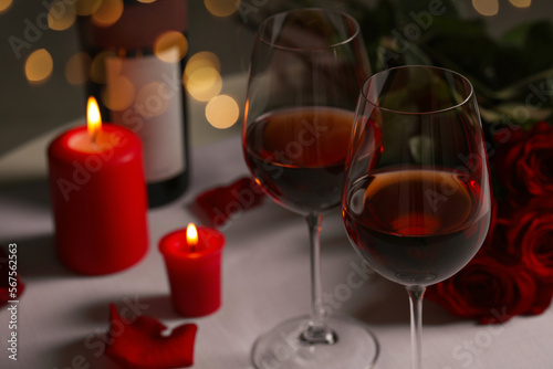 Romantic table setting with glasses of red wine  rose flowers and burning candles