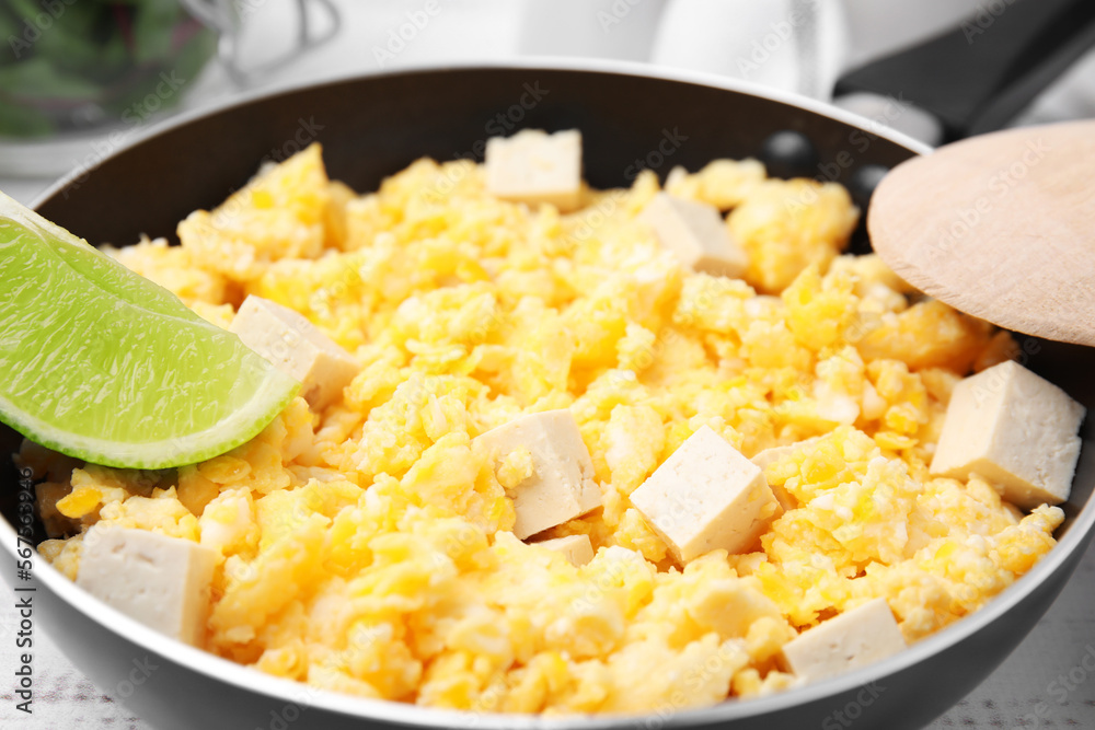 Frying pan with delicious scrambled eggs, tofu and lime, closeup Frying pan with delicious scrambled eggs, tofu and lime, closeup