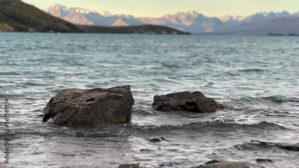 Two large boulders in shallow waters of alpine glacier lake during golden hour