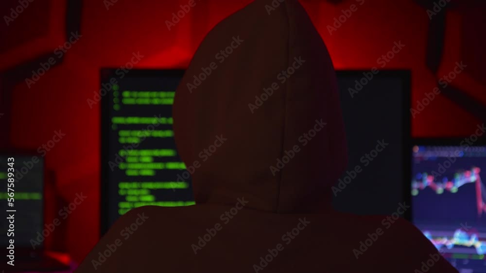 Anonymous hacker in a dark room with multiple monitors writing code. Anonymous hacker in a dark room with multiple monitors writing code.