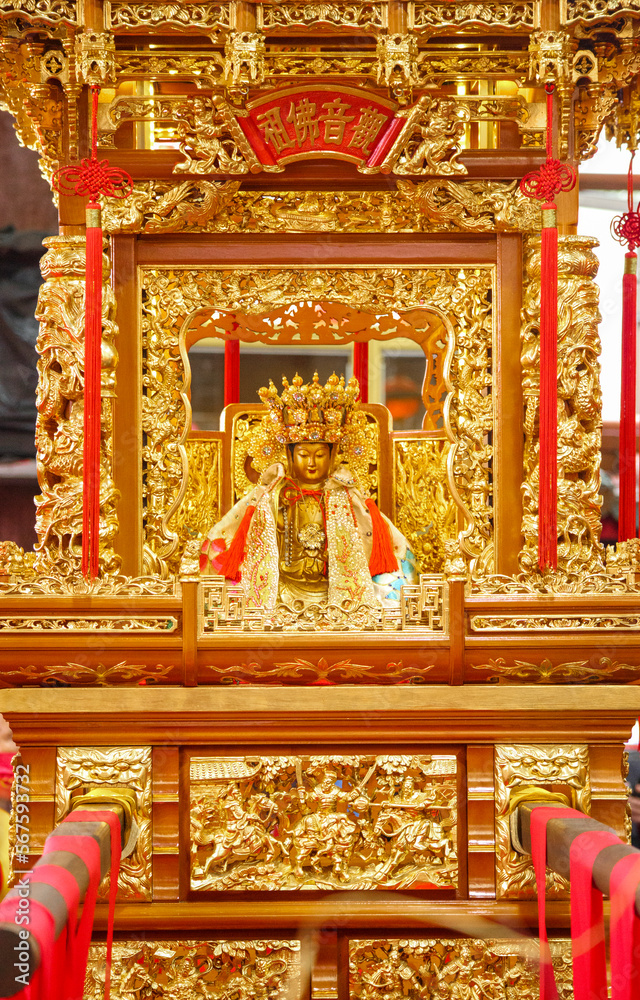 close-up of a gold god statue on a sedan chair, Chinese words means the name of bodhisattva