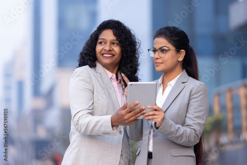 Photography Two businesswomen working on a tablet outdoors.