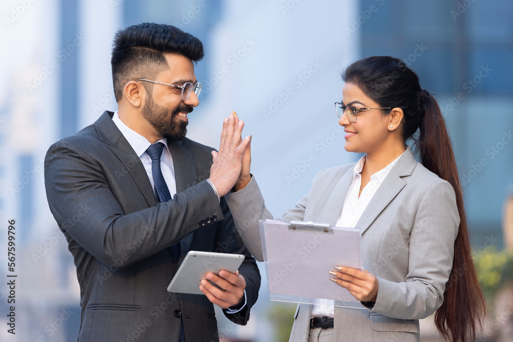 Indian businessman and businesswoman using digital tablet on city street. Indian businessman and businesswoman using digital tablet on city street.