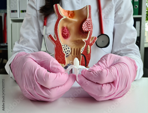 Proctologist doctor inserting rectal suppository into artificial model of human rectum