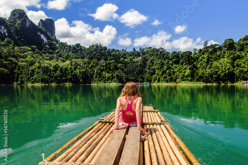 Beautiful young girl discovering the wonders of Ratchaprapa by bamboo raft (Thailand)