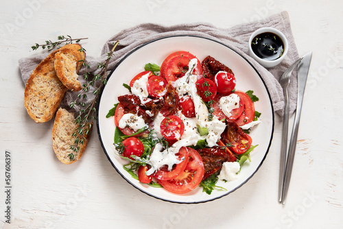Fotografie Delicious caprese salad with tomatoes and mozzarella cheese with fresh leaves