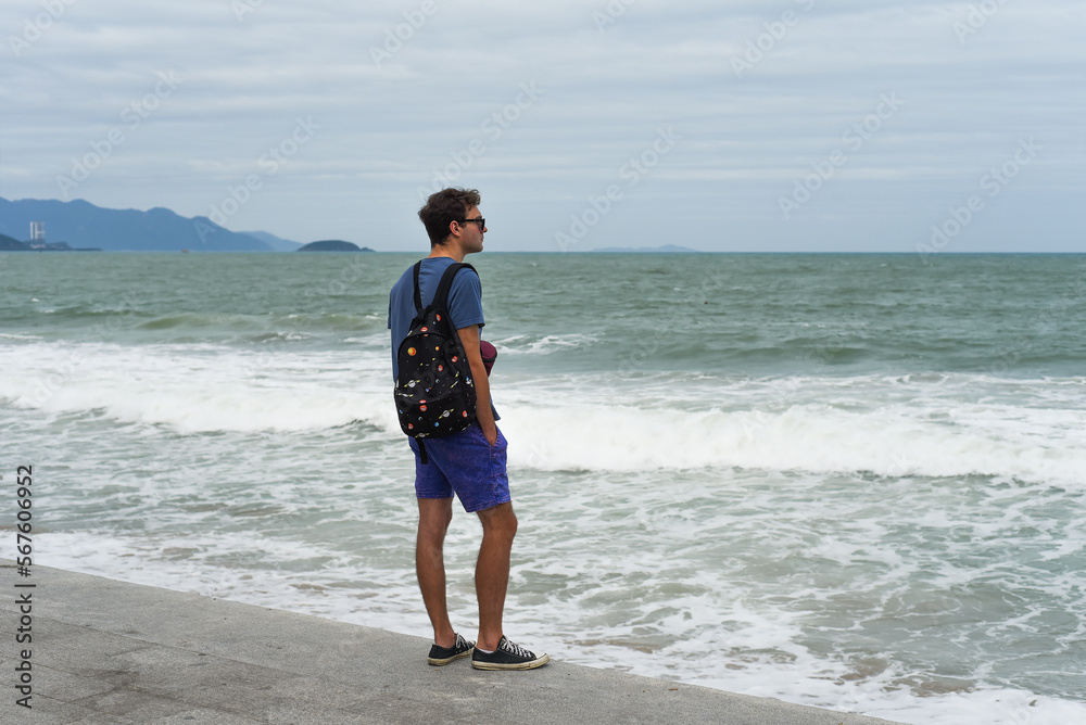 Sad man looks at a stormy sea in bad weather as a depressive concept