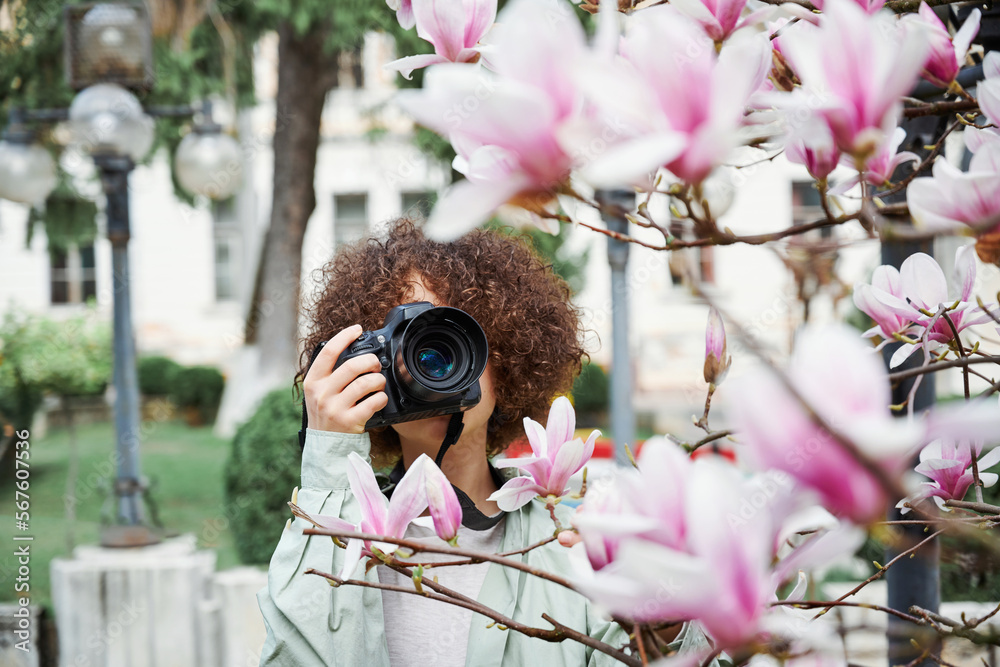 In front of the pink magnolia buds in the spring park, a girl ...
