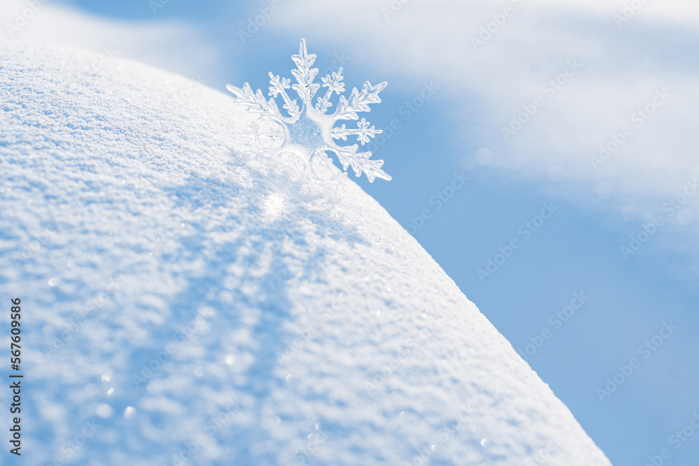 Beautiful ice crystal lies in the snow and glistens in the sun, bokeh in the blue background