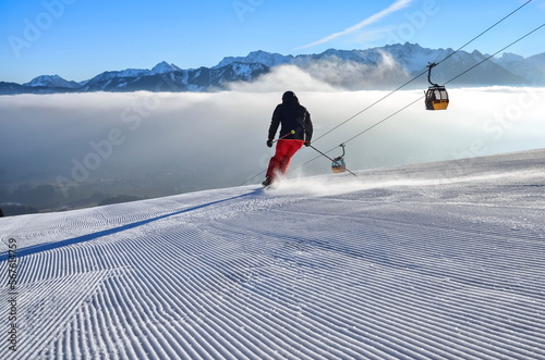 Skifahren, Skiläufer auf Piste mit Panorama auf Winterlandschaft, Berge, Nebel im Tal, Schnee und Gondel