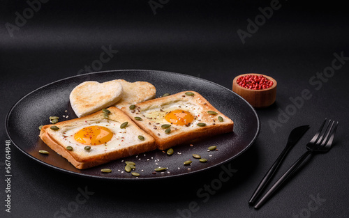 Heart shaped fried egg in bread toast with sesame seeds, flax seeds and pumpkin seeds on a black plate