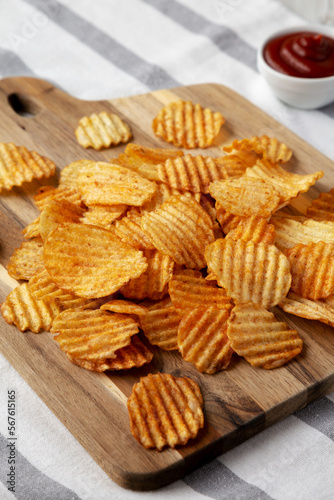 Barbeque Potato Chips on a wooden board, side view.
