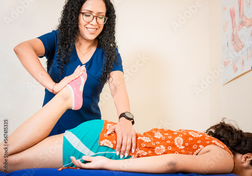 Fotobehang Physiotherapist woman assisting knee to lying patient
