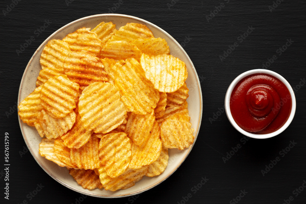 Barbeque Potato Chips on a plate on a black background, top view. Flat lay, overhead, from above.