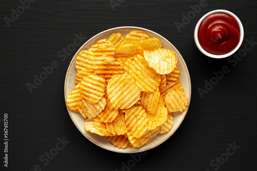 Barbeque Potato Chips on a plate on a black background, top view. Flat lay, overhead, from above.