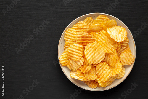 Barbeque Potato Chips on a plate on a black background, top view. Flat lay, overhead, from above. Copy space.
