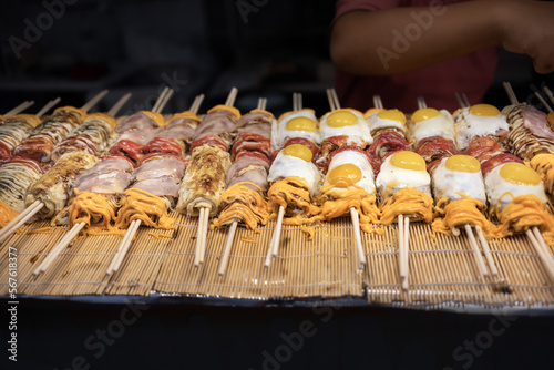 Street food , Japanese Pizza or Okonomiyaki roll on top egg ,cheese and bacan with chopsticks  ready to eat. photo