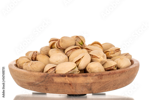 Many peeled pistachios in a wooden bowl, close-up, isolated on white.