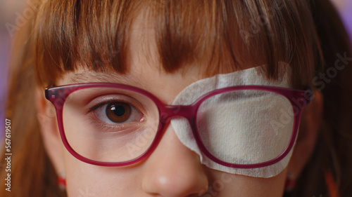 Photography Close-up portrait of sick ill girl face looking at camera, having protective bandage plaster patch scratch on one eye