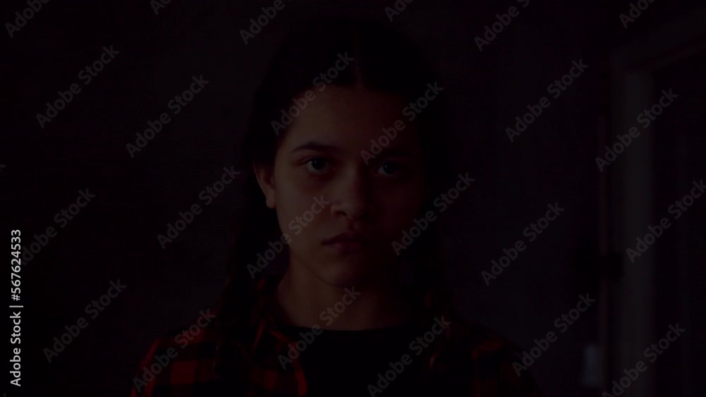 Spooky mysterious cute teenage girl frightening someone in darkness, saying boo in light of flashlight. looking with cold blooded stare , expressing threats and horror during Halloween holiday. Spooky mysterious cute teenage girl frightening someone in darkness, saying boo in light of flashlight. looking with cold blooded stare , expressing threats and horror during Halloween holiday.