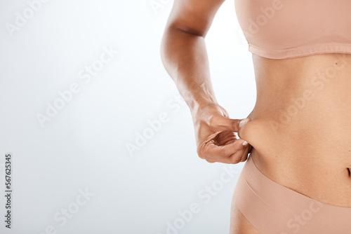 Woman, hand or holding stomach fat for liposuction, weight loss or cosmetic surgery procedure on isolated studio background. Zoom, model or waist skin for cellulite tummy tuck or body wellness mockup photo